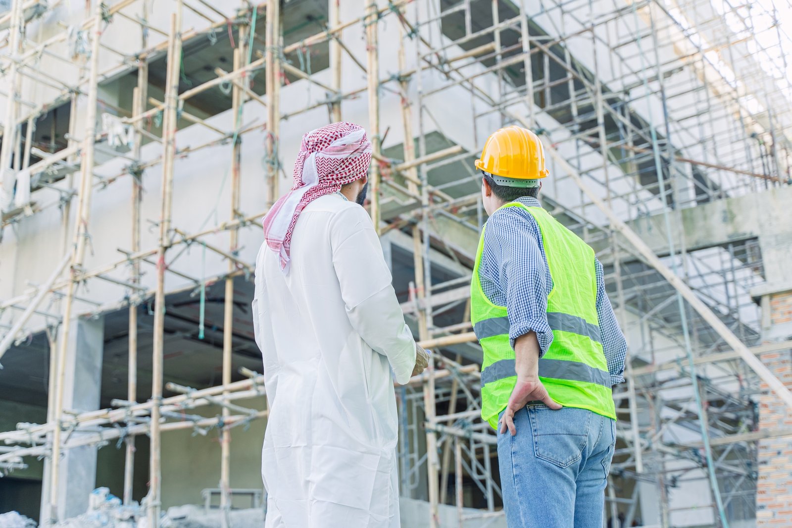 engineer standing with arub property investor looking under construction building